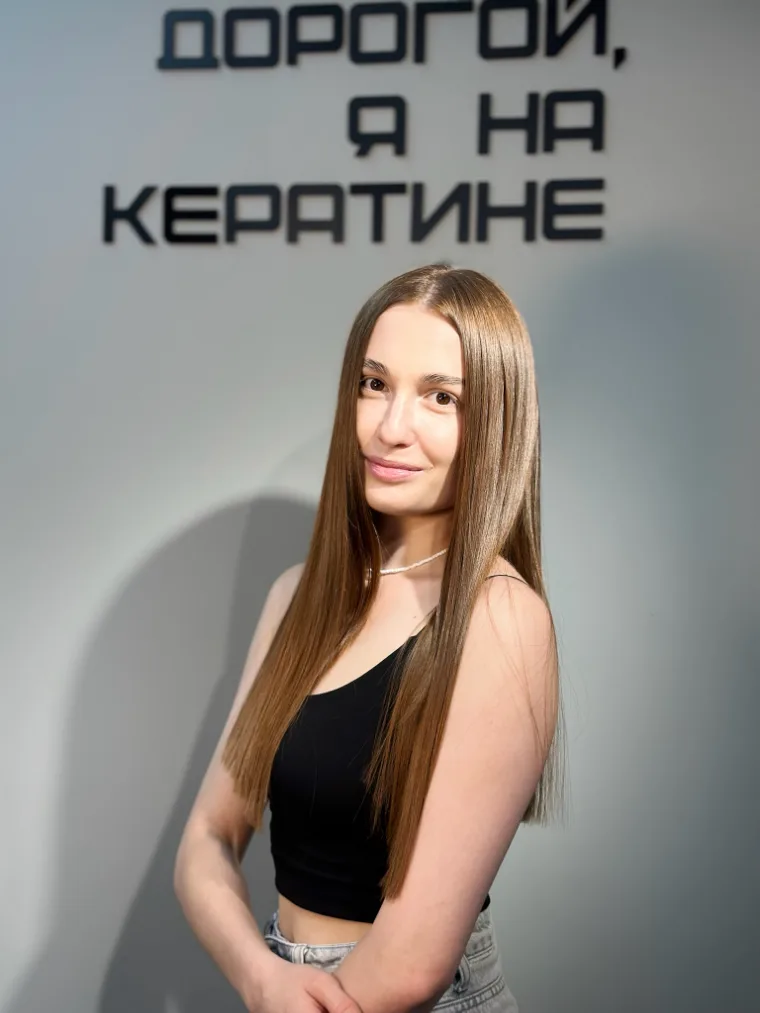 Гостья с длинными русыми волосами у надписи на стене студии